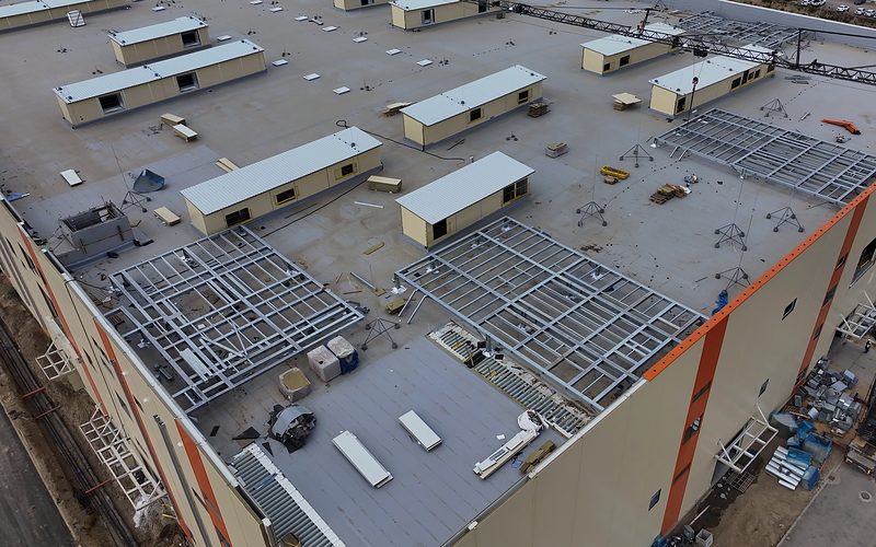 Acél technológiai tartókeretek szerelés közben egy ipari épület lapostetején, légi felvétel